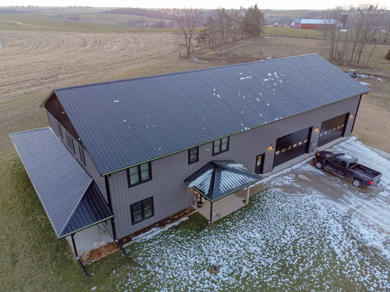 Aerial view of a long barndominium with grey metal siding and a metal roof in Wisconsin farm country