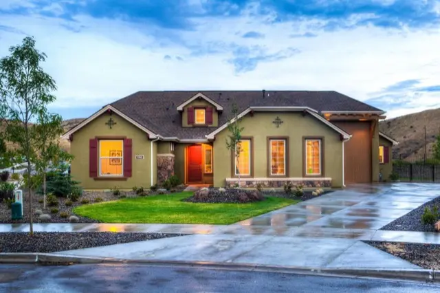 A single-story house with a wide wet concrete driveway leading from the street to the garage