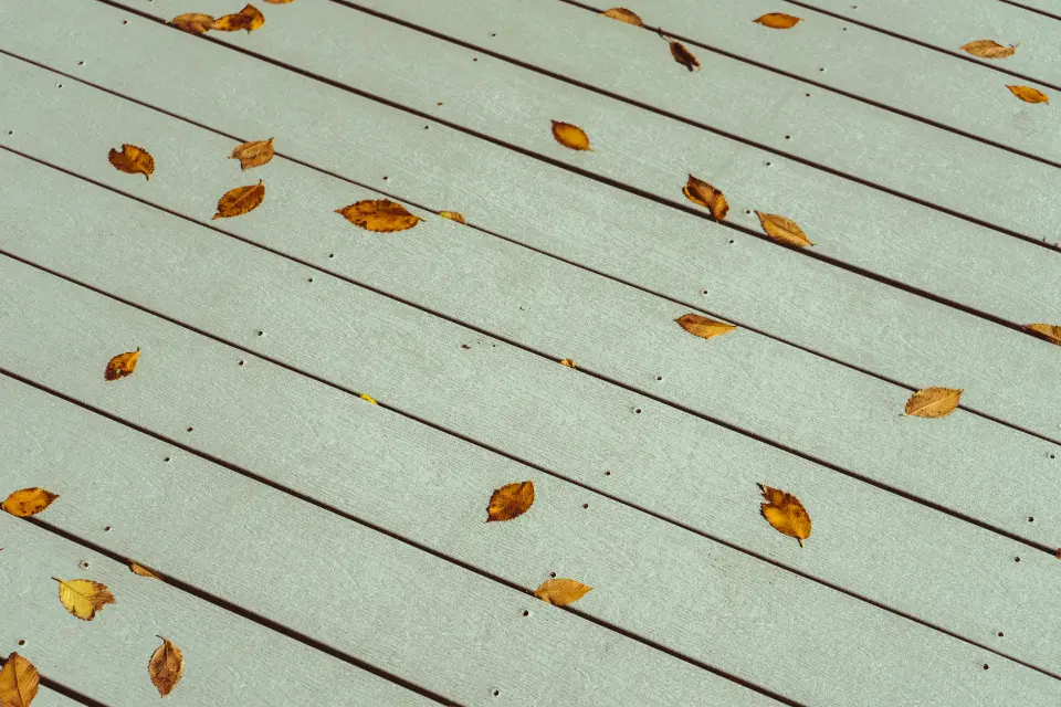 Close-up of grey deck boards with a few fallen autumn leaves
