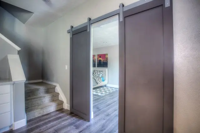 A finished interior with grey walls, a sliding barn door and a short flight of stairs