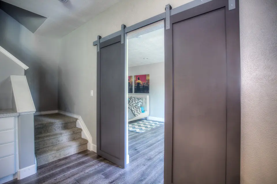 A finished interior with grey walls, a sliding barn door and a short flight of stairs