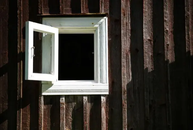 Four white-framed windows with grey trim on a white clapboard house under a red tile roof