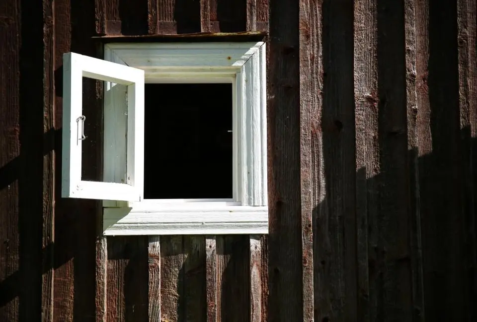 Four white-framed windows with grey trim on a white clapboard house
