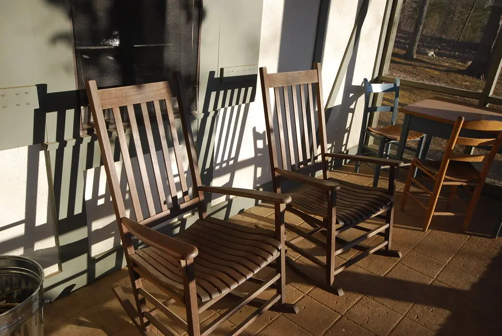 Wooden rocking chairs in late afternoon light on a screened porch